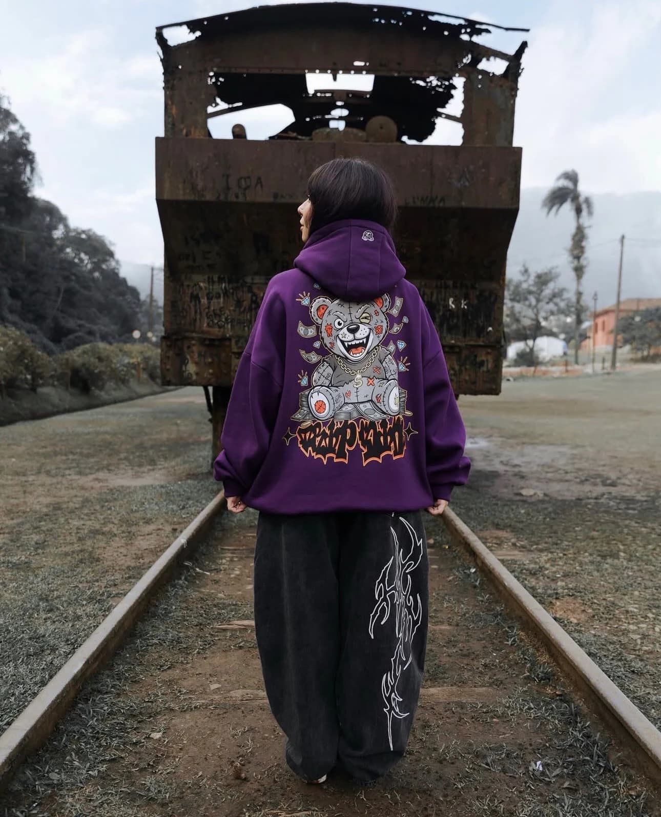 Moletom roxo do ursinho, de costas, na linha do trem